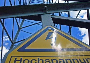 "Blick auf einen Stommast mit Schild Hochspannung"