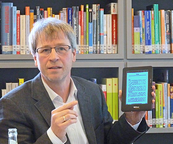 Vor einem Buchregal einen E-Book-Reader in der Hand - der Leiter der Marburger Stadtbücherei Jürgen Hölzer. Foto Hartwig Bambey