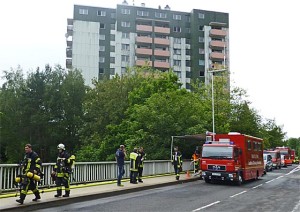 Erschöpfte Feuerwehrleute nach stundenlagem Einsatz, im Hintergrund das Hochaus, in dessen Keller am 25. Juni 2014ein Feuer ausgebrochen war. Sternbald-Foto Hartwig Bambey