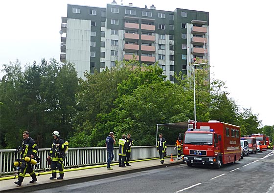 Erschöpfte Feuerwehrleute nach stundenlagem Einsatz, im Hintergrund das Hochaus, in dessen Keller ein Feuer ausgebrochen war. Foto Hartwig Bambey