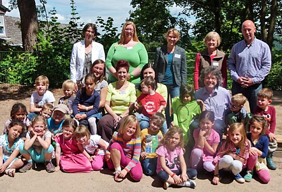 Ernennung der KiTa 'Unter dem Gedankenspiel' in Marburg-Wehrda zum 'Familienzentrum Gedankenspiel'. Hintere Reihe von links: Stefanie Lambrecht, Fachdienstleiterin Kinderbetreuung, Melanie Hotop, Familienpatin, Dr. Mara Meske, Einrichtungsleiterin KiTa, Irmi Rauff, stellvertretende KiTa-Leitung, und Dirk Vaupel, Ortsvorsteher Wehrda. Vordere Reihe von links: Sandra Frommhold, Pädagogin, Jesscia Mühlhans, Familienpatin, Tretyana Paskal, Familienpatin, Bürgermeister Franz Kahle und Kinder der Kindertagesstätte. Foto Lea Trotte