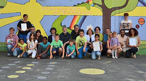  Das neue Wandgemälde an der Bildungsstätte Richtsberg als Beispiel für eines der drei Siegerprojekte. (2. Reihe hockend von links) Peter Schmittdiel, Fachdienst 51, Carin Götzfried, 2. Vorsitzende Bürgerinitiative für Soziale Fragen e.V. (BSF), Bürgermeister Franz Kahle, Bernd Hannemann, Mitglied des Ortsbeirates, Heinrich Scherer, Fachdienst 61, Erika Lotz- Halilovic, Vorsitzende des Ortsbeirates Richtsberg, Elke Siebler, Bildungsstätte Richtsberg, Roger Bergmann, GeWoBau sowie die Vertreterinnen und Vertreter der Kindertagesstätten Berliner Straße und Eisenacher Weg mit den Kindern. Foto Tina Eppler