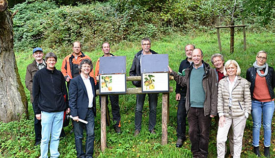 Franz Kahle, Bürgermeister der Universitätsstadt Marburg (vordere Reihe, 2.v.l.) übergibt gemeinsam mi Norbert Clement, Obst- und Gartenbauberater des Landkreises Marburg-Biedenkopf (vordere Reihe, 2.v.r.), Maria Florschütz, Geschäftsführerin der Jugendkonflikthilfe Marburg (vordere Reihe, 1.v.r.), Wolfgang Schuchart, vom  Bund für Umwelt und Naturschutz (hintere Reihe, 2.v.r.) und weiteren am Projekt beteiligten Personen das neue Info-Tafel-System am ‚Apfellehrpfad’. Foto Jonas Becker