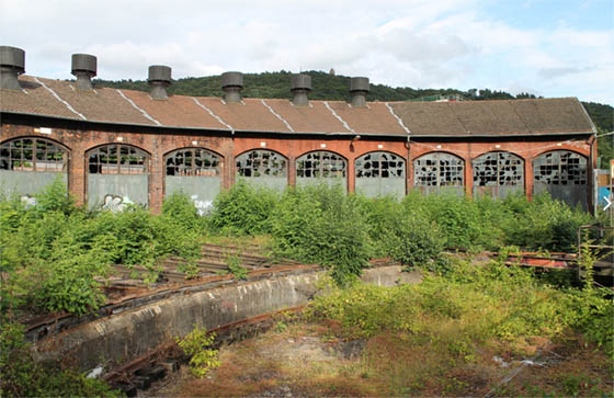 Teilansicht des Lokschuppens von der Bahnseite. Bei dem Denkmal sind inzwischen Teile des Daches eingestürzt, nachdem jahrelang für den Erhalt nichts getan worden ist. Foto Sven Krebs cc, Wikipedia