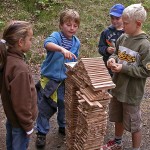 Kinder stehen um Turm aus Holzteilen